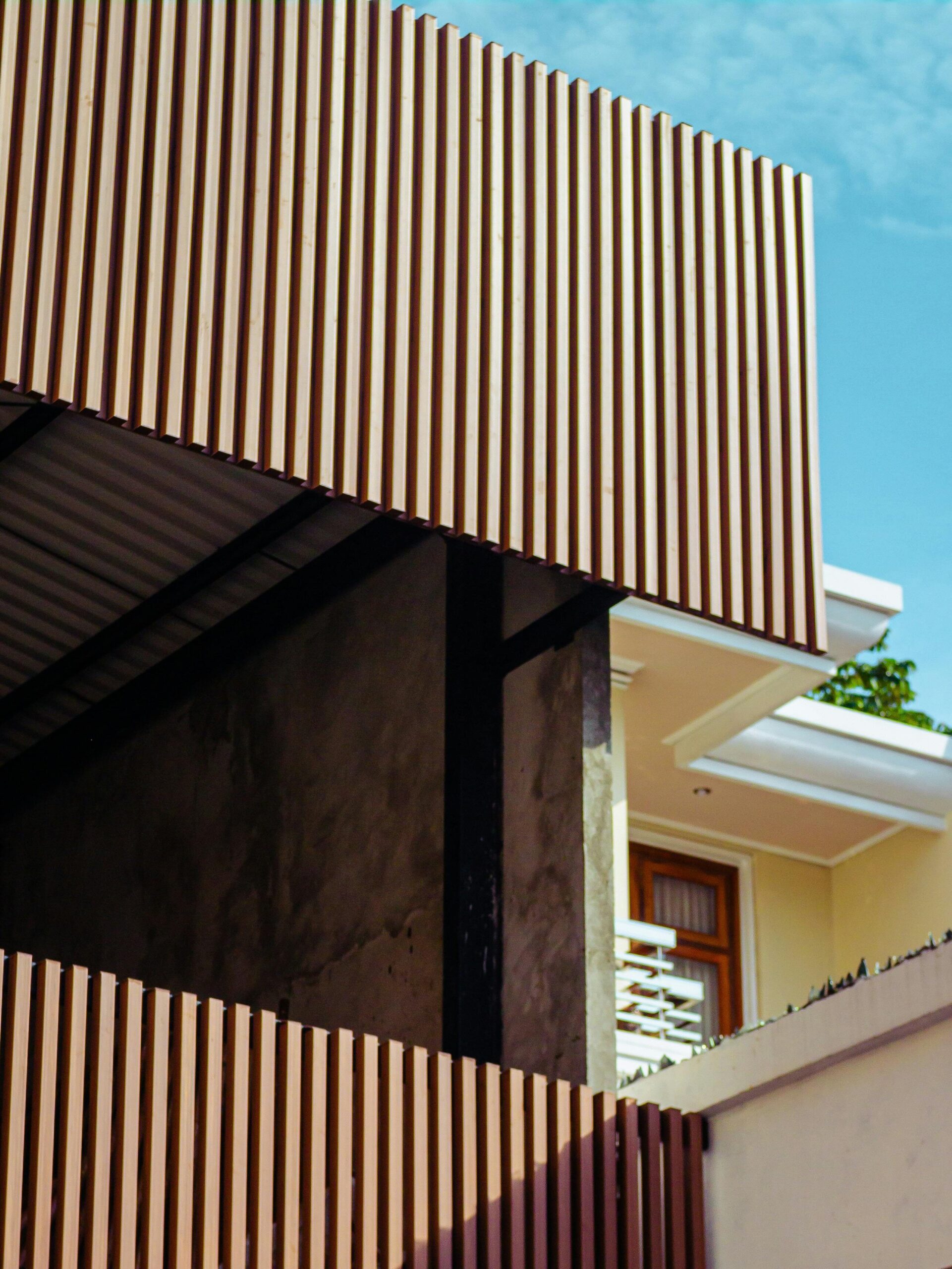 Contemporary building facade featuring wooden slats and angular design elements against a clear sky.